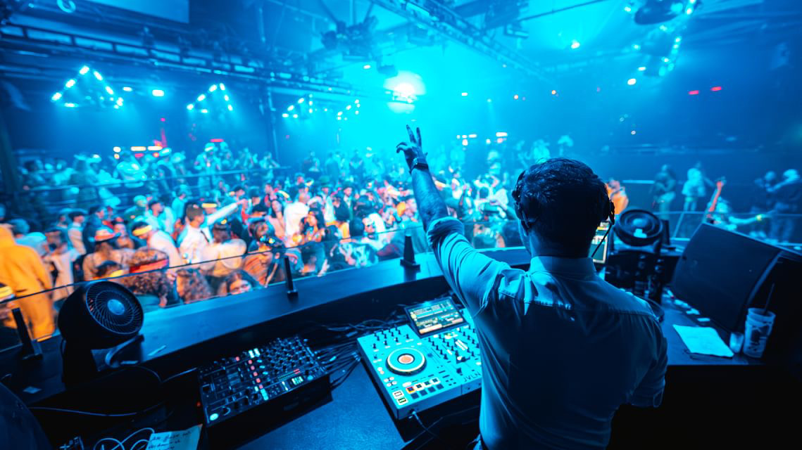DJ vor einer vollen Tanzfläche bei einer Firmenfeier